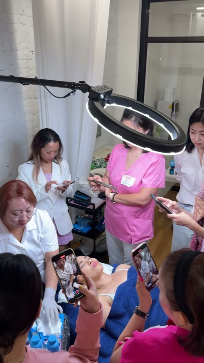 Seminar attendees gathered around a treatment bed filming a live Superjection demonstration