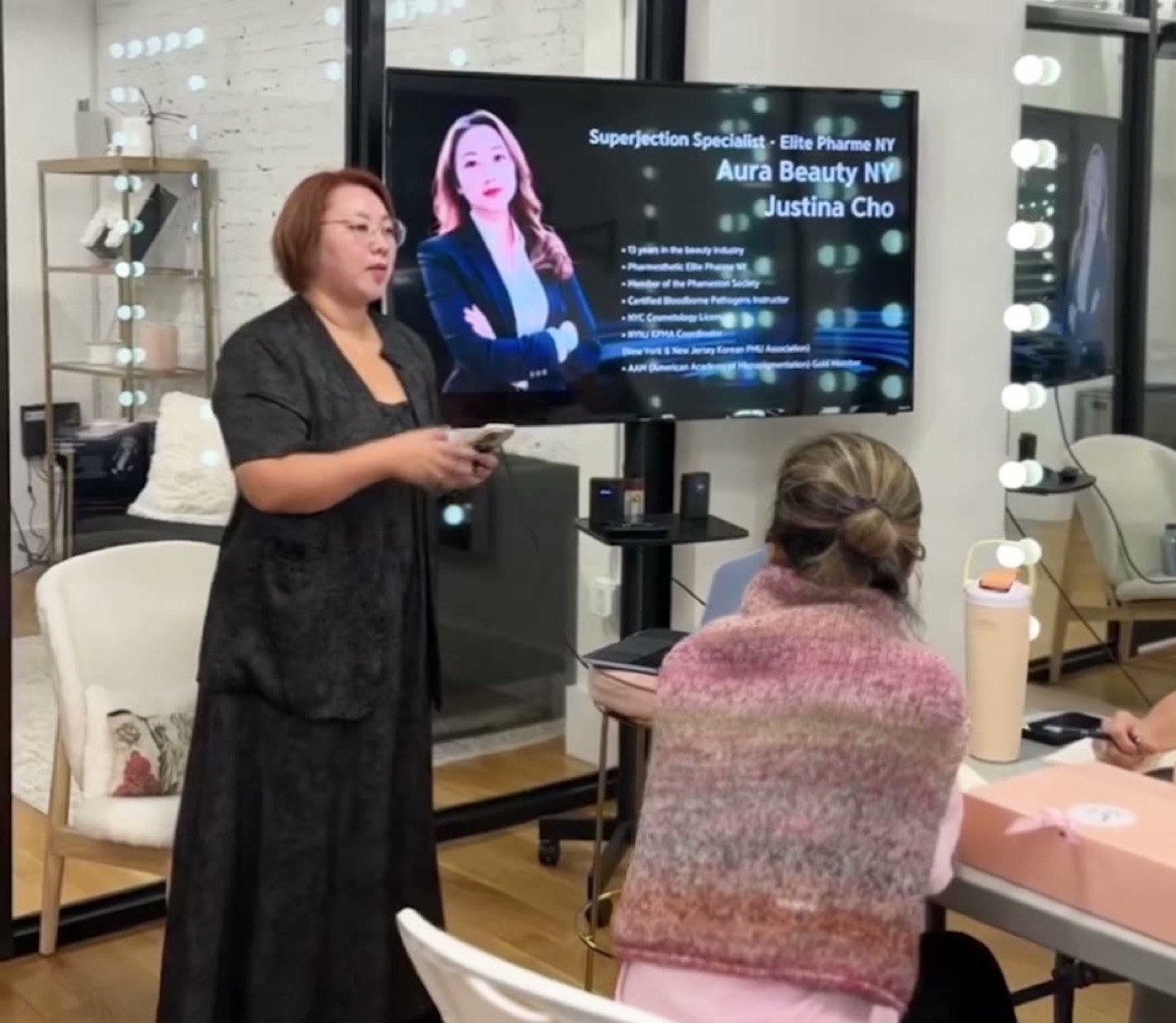 Justina Cho presenting a Superjection session at Aura Beauty, her Elite Pharme NY credentials on screen behind her