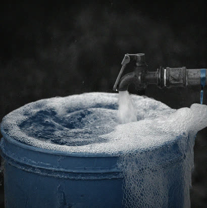 Clean water running from the new well's tap into a blue collection drum