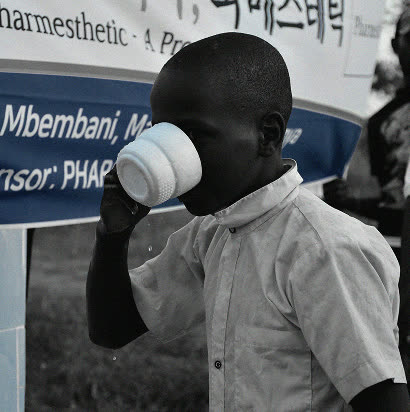 A boy drinking clean water from a cup at the completed Pharmesthetic well site in Kenya